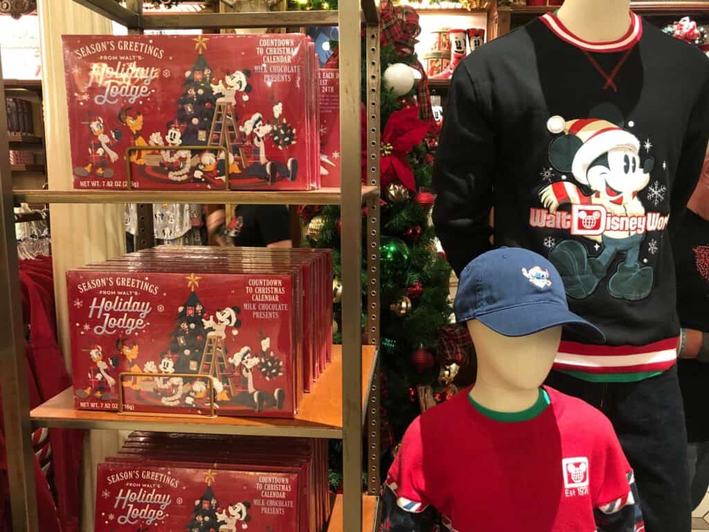 Disney Very Merriest holiday merchandise display at Magic Kingdom featuring festive gift sets, a cheerful Mickey Mouse sweater, and a child mannequin dressed in holiday attire—perfect souvenirs to capture the magic of Disney After Hours celebrations.