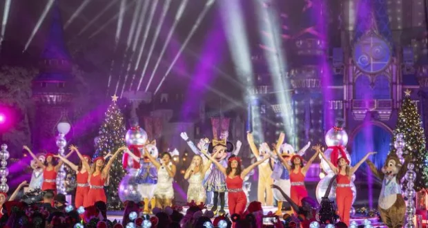 Mickey Mouse, beloved Disney characters, and talented performers dazzle the audience alongside sparkling stars, dancing across a brilliantly illuminated stage adorned with festive Christmas trees and a stunning castle backdrop during the magical Disney Parks Holiday Specials.