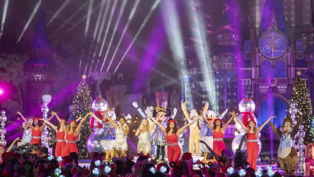 Mickey Mouse, beloved Disney characters, and talented performers dazzle the audience alongside sparkling stars, dancing across a brilliantly illuminated stage adorned with festive Christmas trees and a stunning castle backdrop during the magical Disney Parks Holiday Specials.