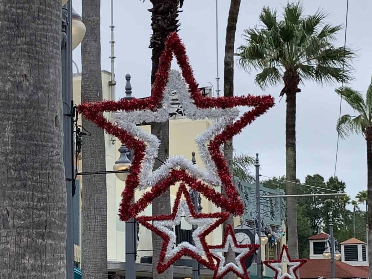 Festive red and white tinsel star decorations dangle from a palm tree along Hollywood Boulevard, bringing holiday cheer to the palm-lined streets of Disney’s Hollywood Studios.