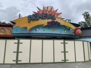 Primeval Whirl sign peeks out from behind construction walls at Disney's Animal Kingdom, with clouds overhead during Destination D23.