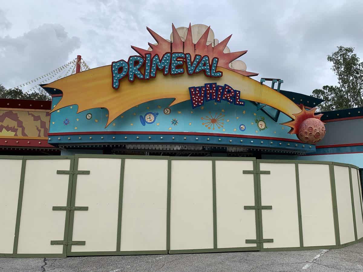 Primeval Whirl sign peeks out from behind construction walls at Disney's Animal Kingdom, with clouds overhead during Destination D23.