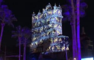 The Hollywood Tower Hotel at Disney’s Hollywood Studios dazzles after dark with vibrant projection mapping and twinkling palm trees in front, bringing the magic of Sunset Seasons Greetings to life for park guests.
