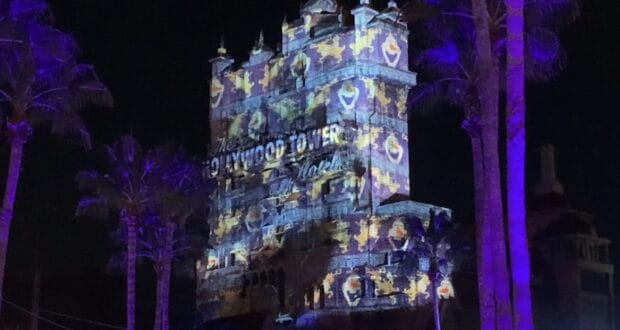 The Hollywood Tower Hotel at Disney’s Hollywood Studios dazzles after dark with vibrant projection mapping and twinkling palm trees in front, bringing the magic of Sunset Seasons Greetings to life for park guests.