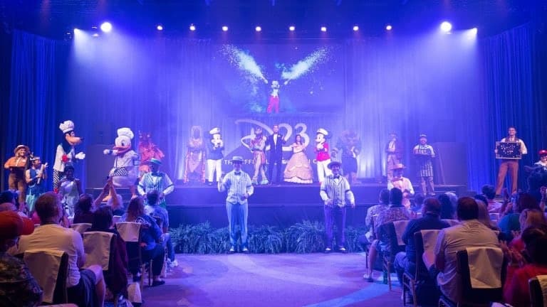 Mickey Mouse and other beloved Disney characters put on a dazzling stage show, captivating the crowd under vibrant blue and purple lights as fans cheer from the audience.