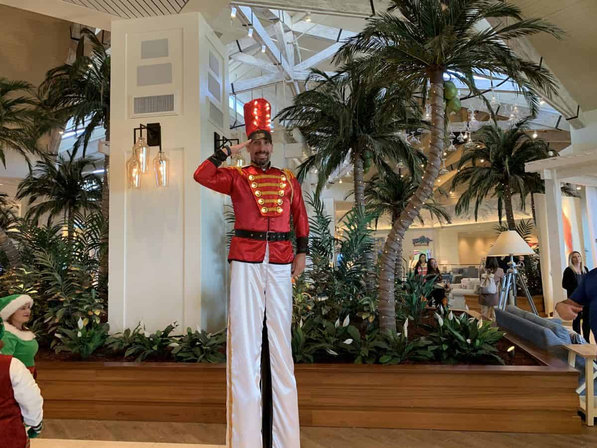 A cheerful toy soldier on tall stilts salutes guests amid tropical palm trees, spreading holiday spirit throughout Margaritaville Resort Orlando’s festive celebrations.