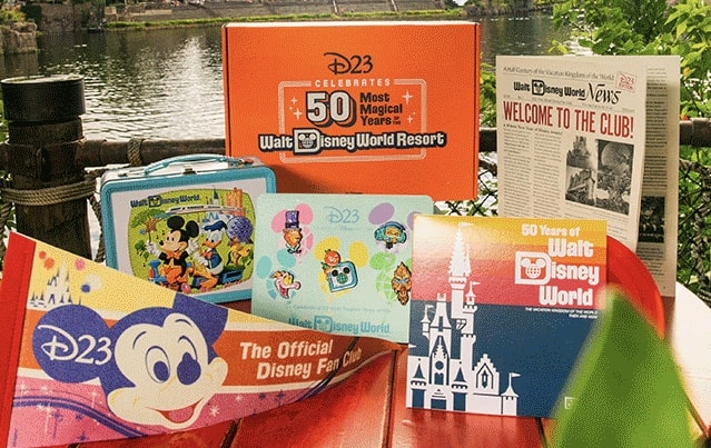 A vibrant display of Disney World’s 50th anniversary collectibles set up along the water, featuring commemorative books and a vintage-style lunchbox, inviting fans to celebrate decades of magic.