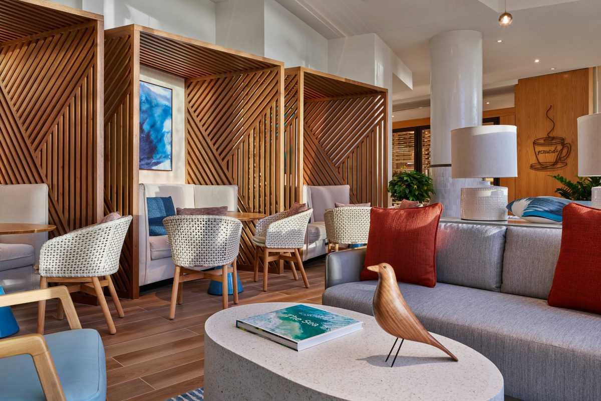 Chic lounge at the Swan Reserve Hotel featuring wood accents, plush seating, vibrant blue and orange pillows, and a whimsical bird figurine on the table—an ideal spot for unwinding after an exciting day exploring Walt Disney World attractions.