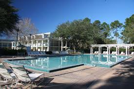 Serene outdoor pool area with rows of inviting lounge chairs, lush greenery, and a grand white resort building in the background—evoking the peaceful atmosphere of Disney Resort Quiet Pools near Walt Disney World, perfect for guests seeking a relaxing break from the theme park excitement.