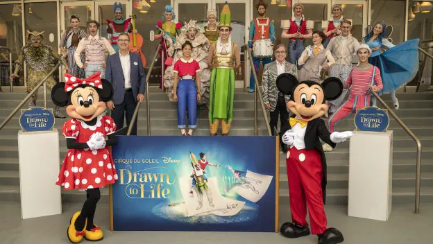Minnie and Mickey Mouse join talented performers and guests on the steps in front of the vibrant "Drawn to Life" sign, coming together for a memorable Disney photo that celebrates the magic of this spectacular show.