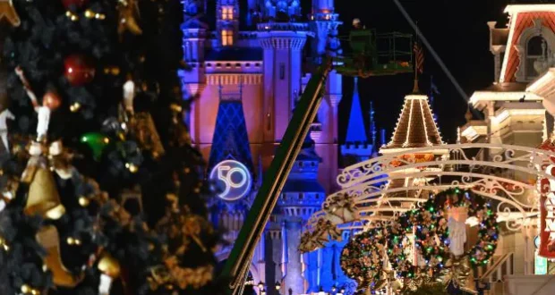 Holiday wreaths and sparkling Christmas decorations illuminate Cinderella Castle at Walt Disney World, with the iconic "50" anniversary emblem glowing in the background, creating a festive atmosphere that feels as magical as Disney’s Halloween celebrations.