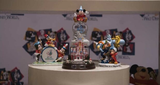 Mickey Mouse, Genie, and other beloved Disney characters as collectible figurines showcased on circular stands inside a themed display setting.