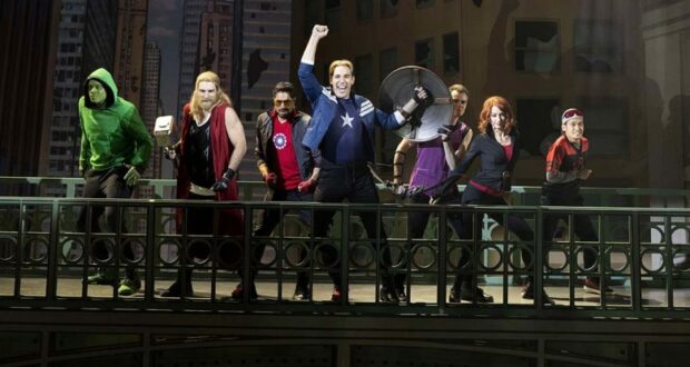 Seven Marvel superheroes strike heroic poses on an Avengers Tower balcony, overlooking the city skyline, ready to greet fans visiting the themed entertainment attraction.