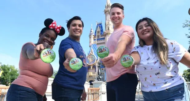 A group of excited adults proudly display green Disney celebration buttons in front of the iconic Cinderella Castle at Disney World, soaking up the enchantment and vibrant energy that makes a grown-up trip to the park unforgettable.