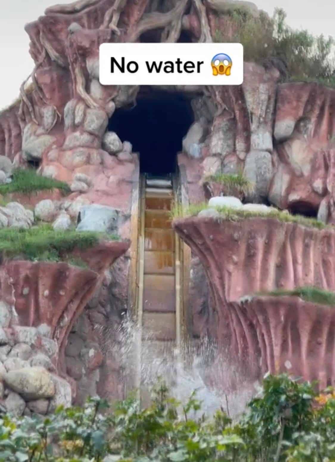 Splash Mountain stands eerily dry, its iconic log flume ride stripped of rushing water. Guests in their log vehicles speed toward the legendary drop, only to be greeted by a bold "No water" sign overhead and experience a bone-dry landing where cascading splashes should be.