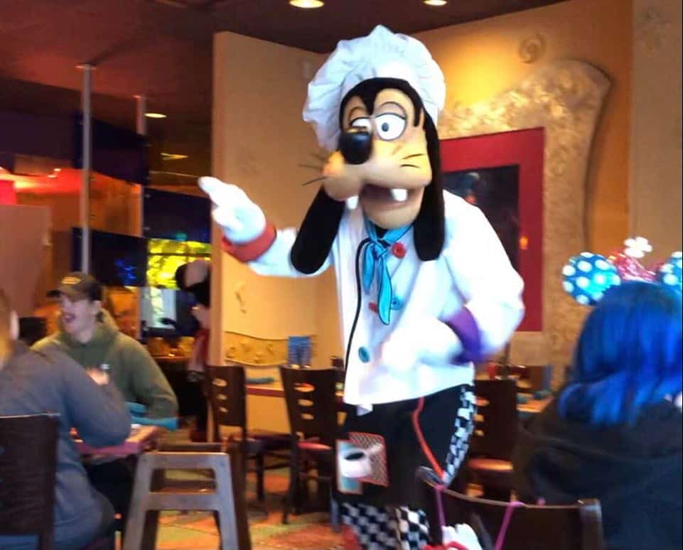 Goofy in his chef outfit greeting diners inside the vibrant, family-friendly dining space at Goofy's Kitchen in Disneyland.