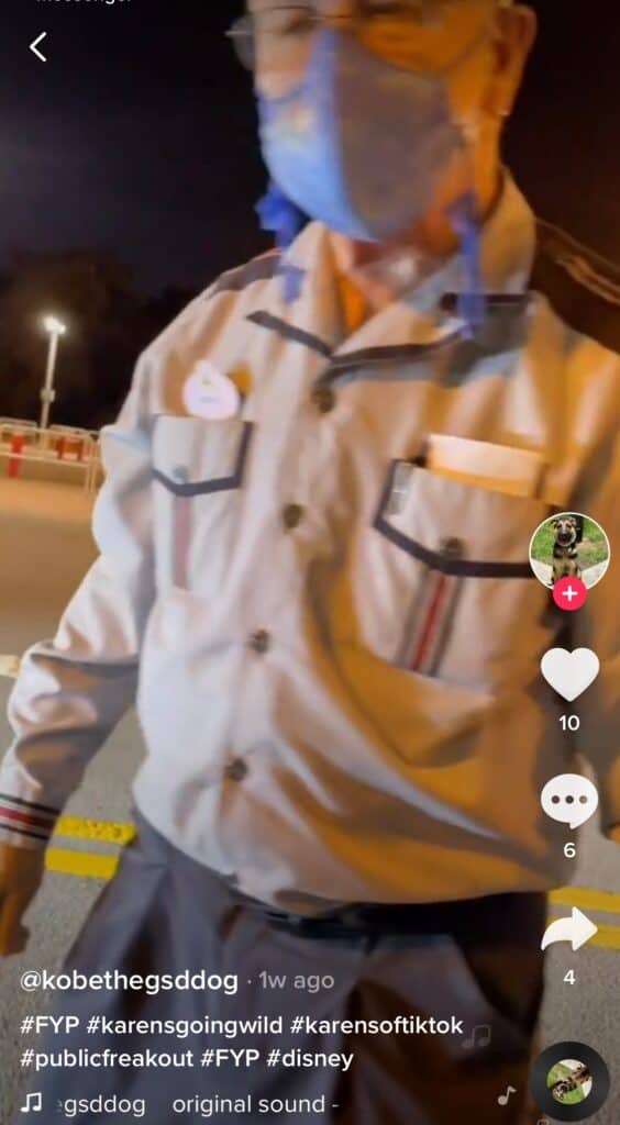 A Disney Cast Member welcomes guests outside at night near a themed barrier, with the TikTok interface overlaying the magical park atmosphere.