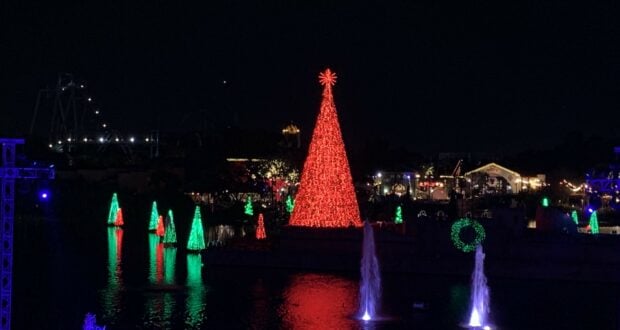 SeaWorld Orlando’s lakefront dazzles with a towering red Christmas tree centerpiece, surrounded by glowing holiday trees and shimmering fountains nightly—an immersive celebration that makes New Year’s Eve at the park truly unforgettable.