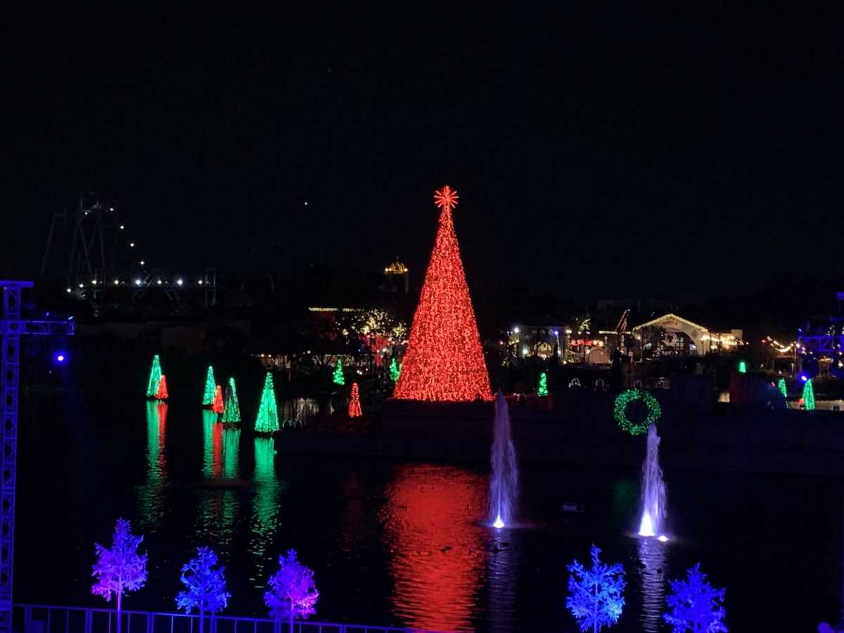 SeaWorld Orlando’s lakefront dazzles with a towering red Christmas tree centerpiece, surrounded by glowing holiday trees and shimmering fountains nightly—an immersive celebration that makes New Year’s Eve at the park truly unforgettable.