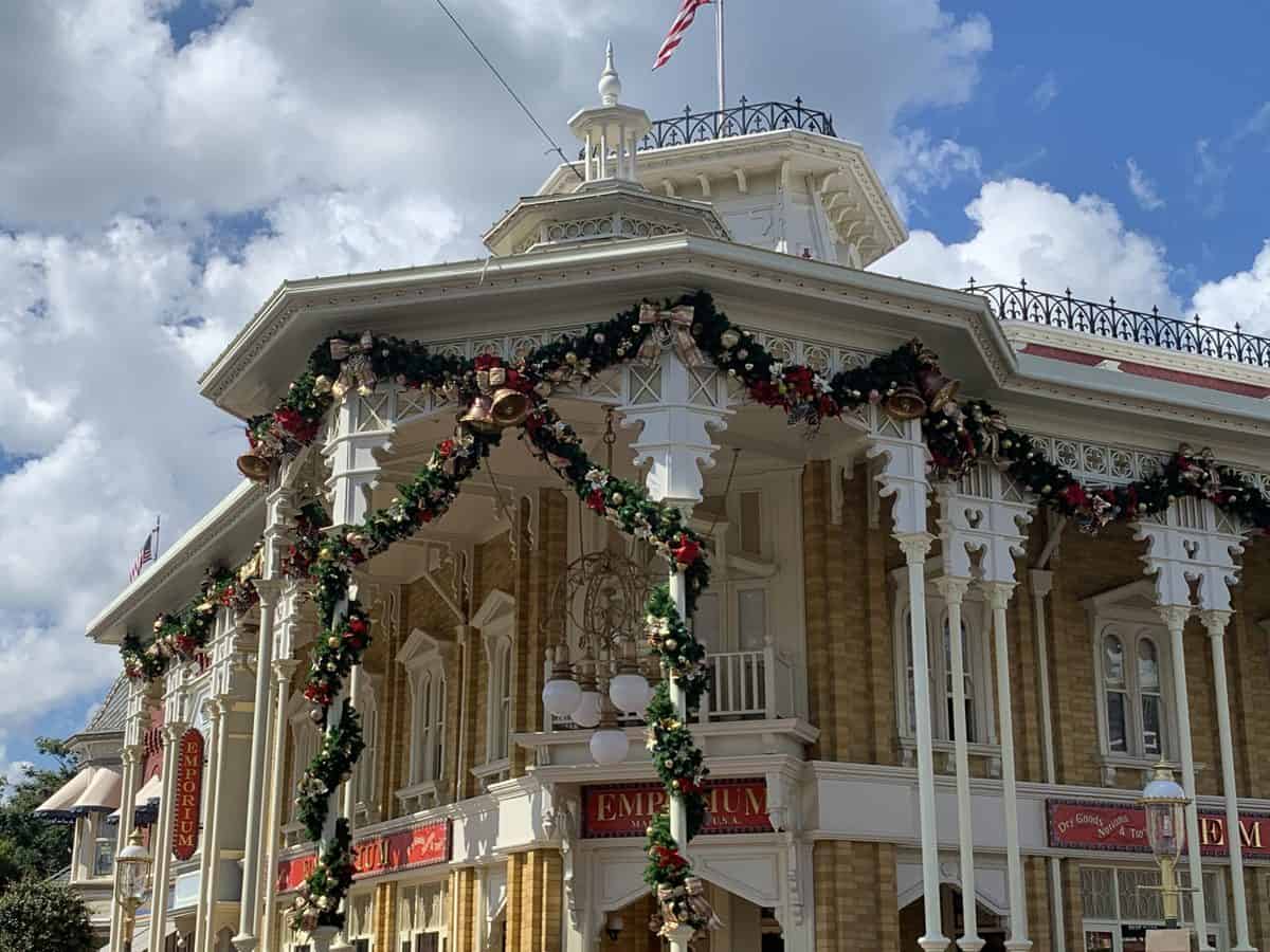 Main Street, U.S.A. dressed in festive Victorian garlands and sparkling Christmas ornaments beneath a partly cloudy sky, inviting guests to enjoy the holiday magic and catch all the seasonal sights without missing a moment of theme park fun.