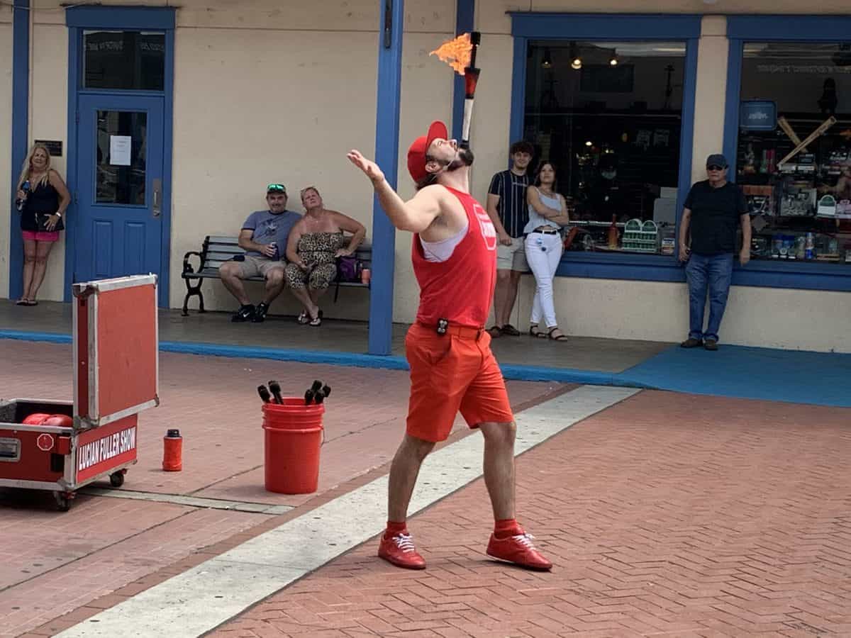 A fire-breathing performer in eye-catching red dazzles guests with fiery stunts on the brick pathway, drawing a crowd at Old Town’s festive New Year’s Eve bash.
