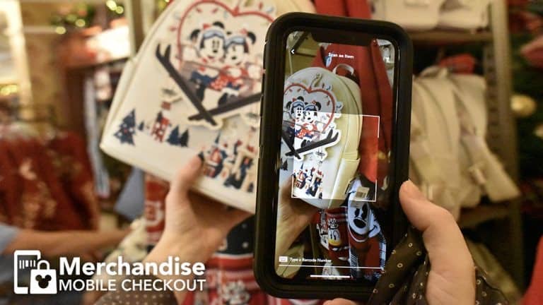 A guest at Disney World scans a Mickey Mouse-themed backpack with their phone for mobile merchandise checkout inside a park store.