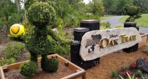 Mickey Mouse topiary posing with a soccer ball beside the Disney’s Oak Trail Golf Course sign and walking path.