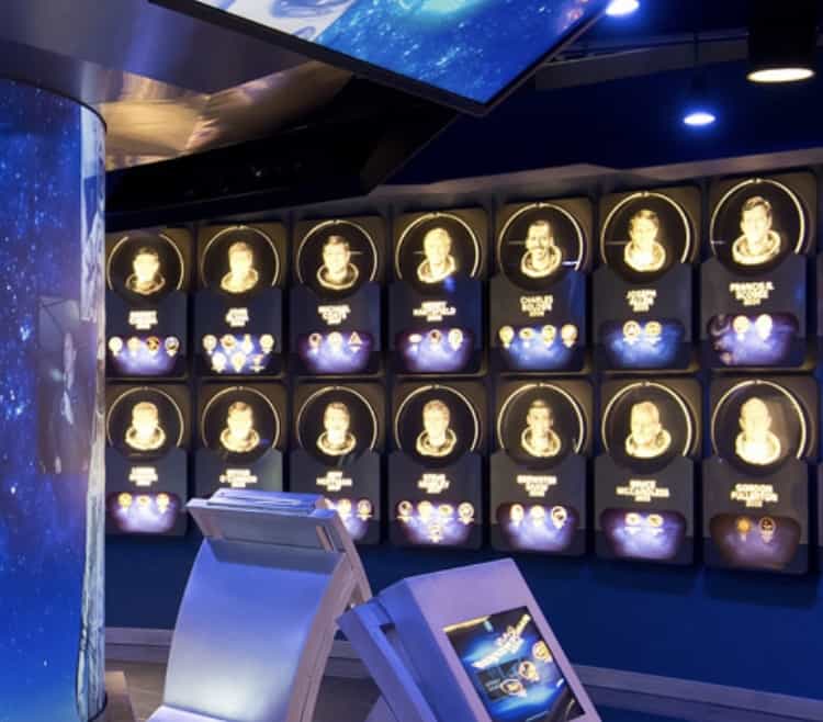 Astronaut portraits glowing on the wall with fun interactive screens at the Kennedy Space Center Visitor Complex exhibit.