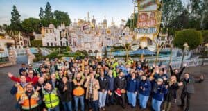 A cheerful crowd gathers and beams with excitement in front of the iconic “It’s a Small World” façade at Disneyland, ready to experience the magic together.