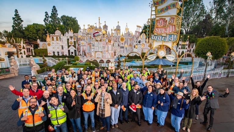 A cheerful crowd gathers and beams with excitement in front of the iconic “It’s a Small World” façade at Disneyland, ready to experience the magic together.
