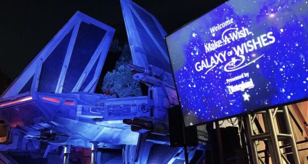 A TIE fighter display illuminated at night near the “Make-A-Wish Galaxy of Wishes” screen in Disneyland’s Star Wars-themed area.