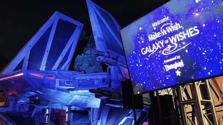 A TIE fighter display illuminated at night near the “Make-A-Wish Galaxy of Wishes” screen in Disneyland’s Star Wars-themed area.