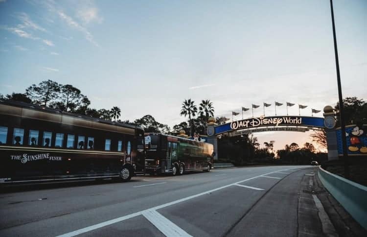 The Sunshine Flyer bus cruises past the iconic Walt Disney World entrance sign at sunset, calling back memories of Disney’s Magical Express and the excitement of fans returning to their favorite parks, especially since January 10th.