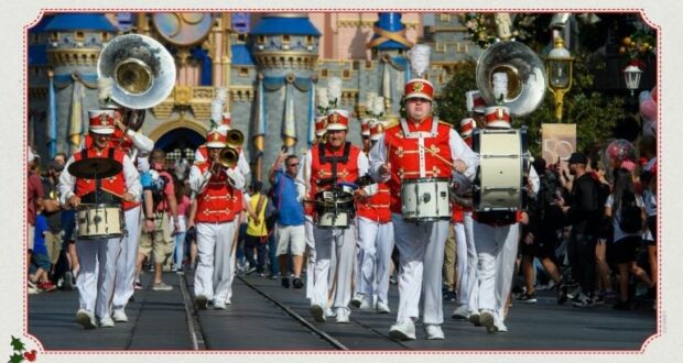 The Main Street Philharmonic in bright red uniforms performs lively tunes as they march down Main Street, U.S.A., with Cinderella Castle and cheering guests filling the background at Magic Kingdom.