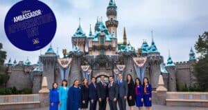 Smiling Disney Ambassadors gather in front of Disneyland’s iconic snow-dusted Sleeping Beauty Castle, celebrating Ambassador Appreciation Day with a commemorative sign that honors the park's cherished tradition and the lasting legacy of its Ambassadors.