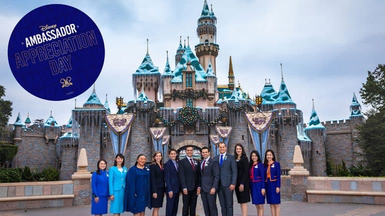 Smiling Disney Ambassadors gather in front of Disneyland’s iconic snow-dusted Sleeping Beauty Castle, celebrating Ambassador Appreciation Day with a commemorative sign that honors the park's cherished tradition and the lasting legacy of its Ambassadors.