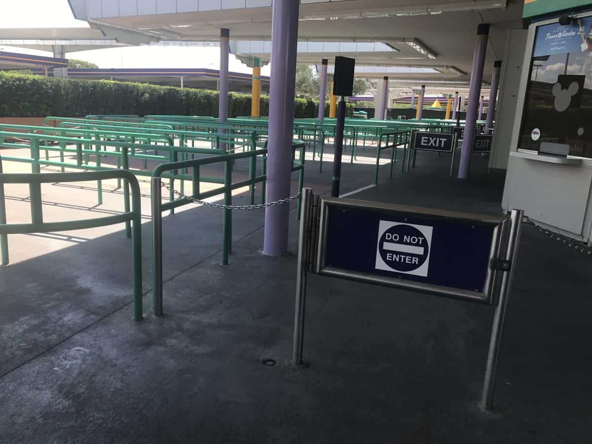 An empty ride queue at the amusement park, green railings guiding the path and a prominent "Do Not Enter" sign marking the closed entrance, evoking that quiet moment in a major theme park just after closing time when all excitement has paused.