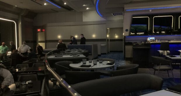 Futuristic Space 220 Restaurant at EPCOT, featuring ambient blue lighting and sleek curved tables filled with guests enjoying the out-of-this-world dining experience—now hiring.