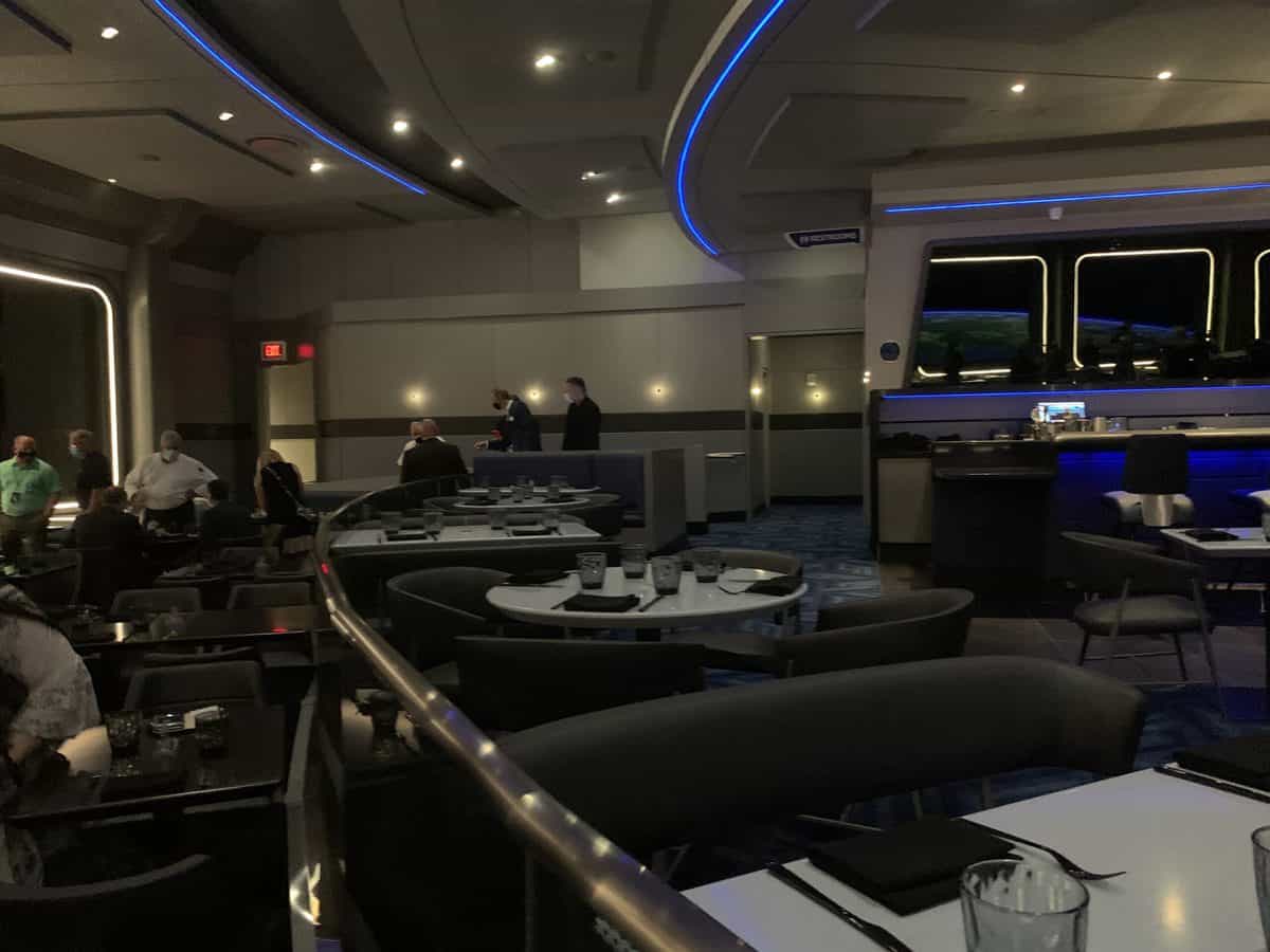 Futuristic Space 220 Restaurant at EPCOT, featuring ambient blue lighting and sleek curved tables filled with guests enjoying the out-of-this-world dining experience—now hiring.