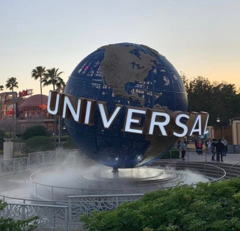 The iconic Universal globe greets guests at Universal Orlando Resort, spinning amid swirling mist as visitors make their way into the park, some still sporting face masks inside certain attractions.
