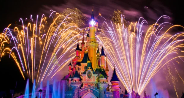 Dazzling fireworks light up the night sky above Sleeping Beauty Castle at Disneyland Paris, as vibrant fountains dance in front, creating an unforgettable spectacle for fans enjoying the park’s legendary Fireworks Show.