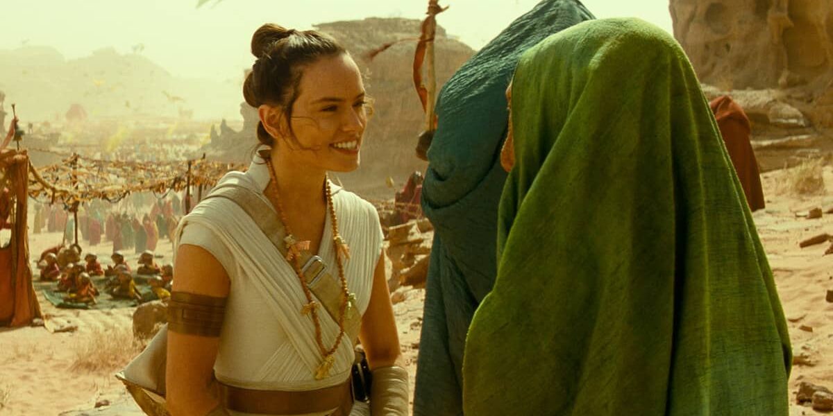 Princess Leia smiles at someone dressed as Boba Fett in Star Wars: Galaxy’s Edge, with other guests exploring the marketplace.