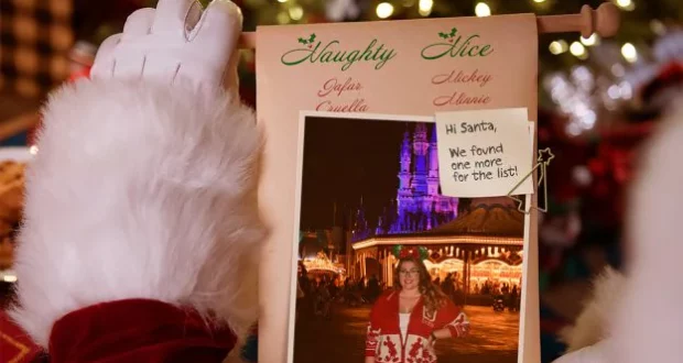 Santa presents his "Naughty List" scroll featuring a photo of a guest enjoying the dazzling holiday lights at Disneyland, highlighting the unforgettable Disney Parks seasonal photo experience.