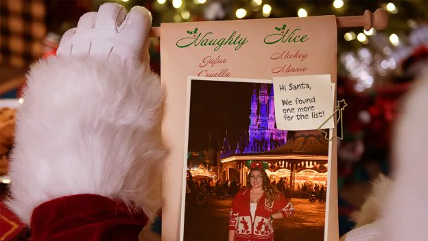 Santa presents his "Naughty List" scroll featuring a photo of a guest enjoying the dazzling holiday lights at Disneyland, highlighting the unforgettable Disney Parks seasonal photo experience.