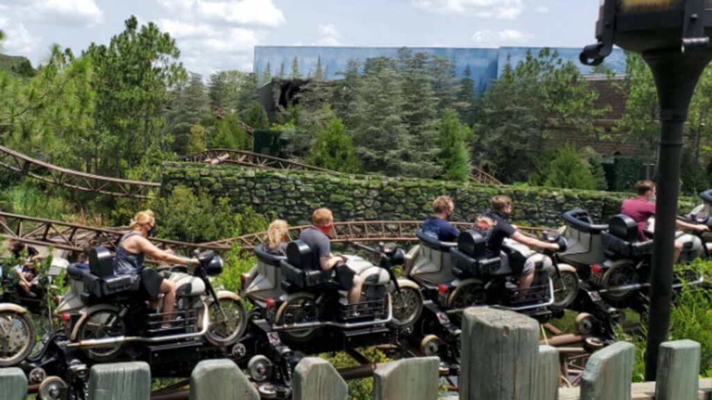 Guests zoom along Hagrid's Magical Creatures Motorbike Adventure in motorcycle-style seats, racing through immersive Forbidden Forest scenery surrounded by lush greenery and towering trees at Universal’s Islands of Adventure.