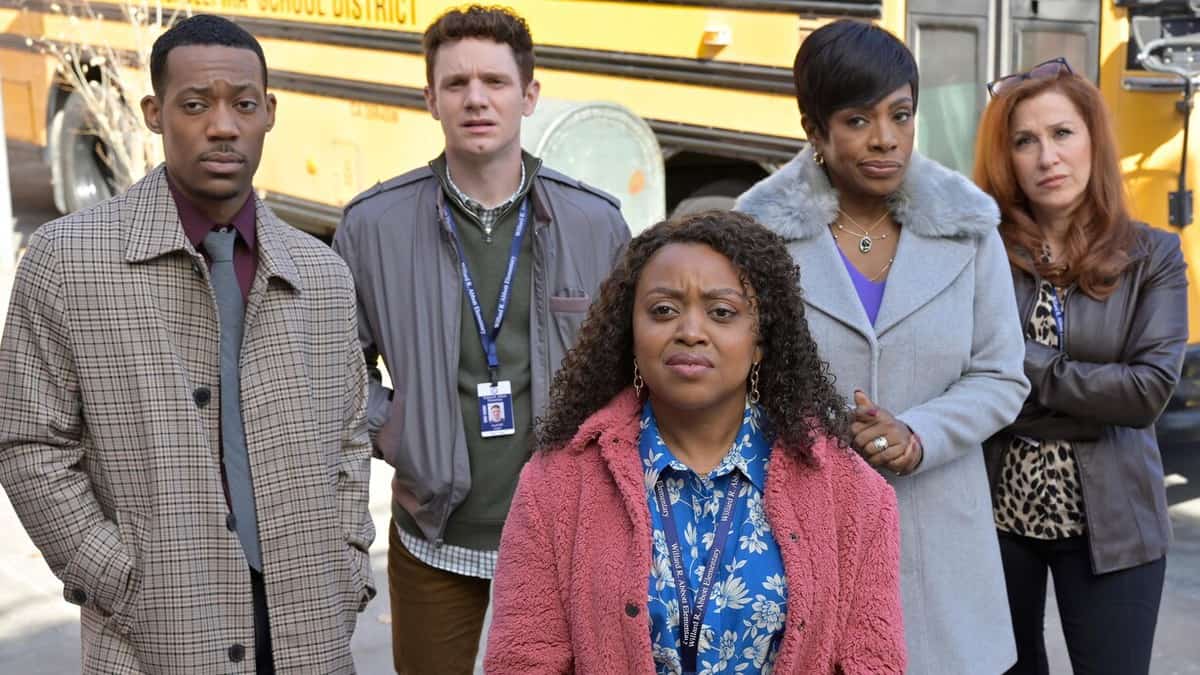The cast of Abbott Elementary stands together outside, posed determinedly in front of a bright yellow school bus, capturing the show's spirited energy for fans rather than just playful classroom antics.