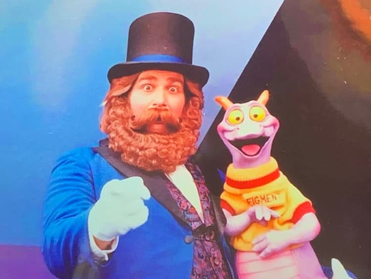 Dreamfinder in his signature blue suit and top hat stands alongside Figment, the iconic smiling purple dragon in a yellow shirt, capturing the beloved EPCOT duo best known from Journey Into Imagination and popular as Figment Popcorn Buckets.