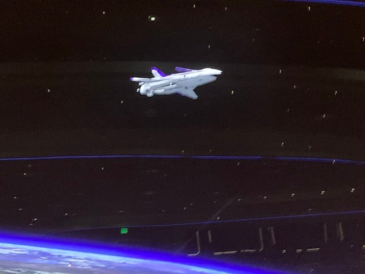A model space shuttle floats above Earth, surrounded by sparkling stars and cosmic blue light, capturing the out-of-this-world dining experience found at EPCOT’s Space 220 Restaurant.