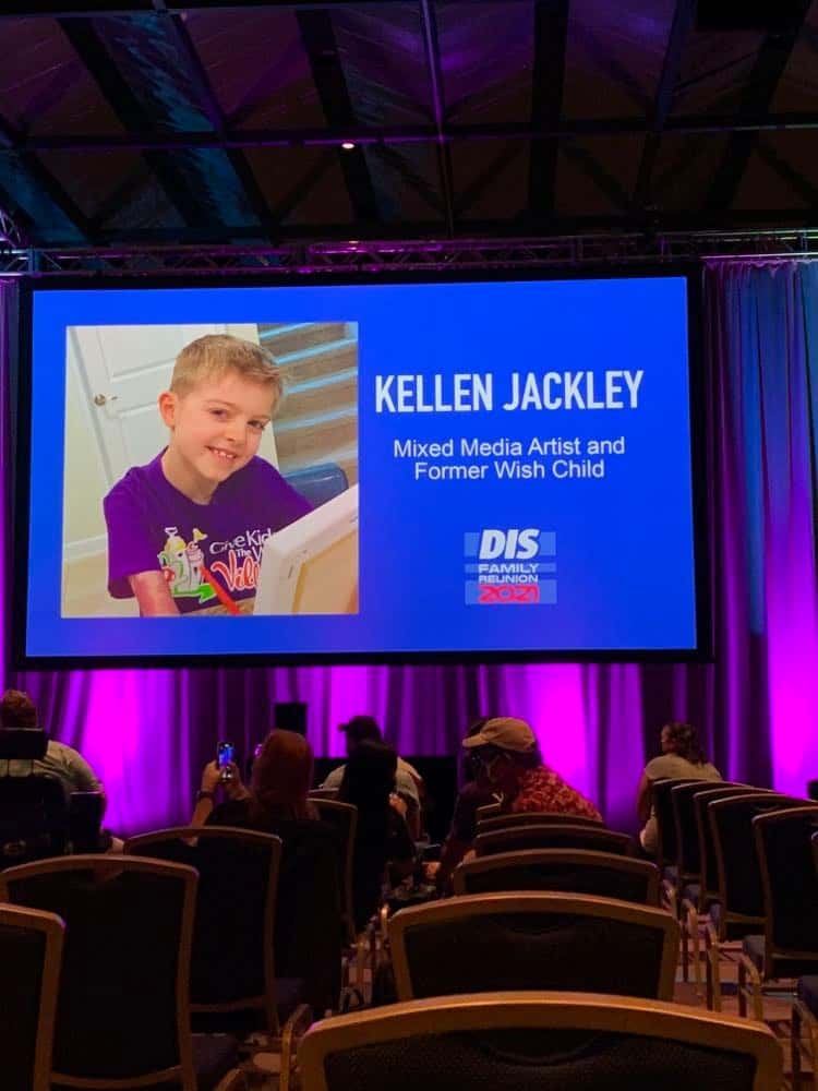 Kellen Jackley captivates Give Kids the World Village guests during a live, interactive presentation in a vibrant purple-lit hall, sharing creative inspiration as part of the World Changer series.