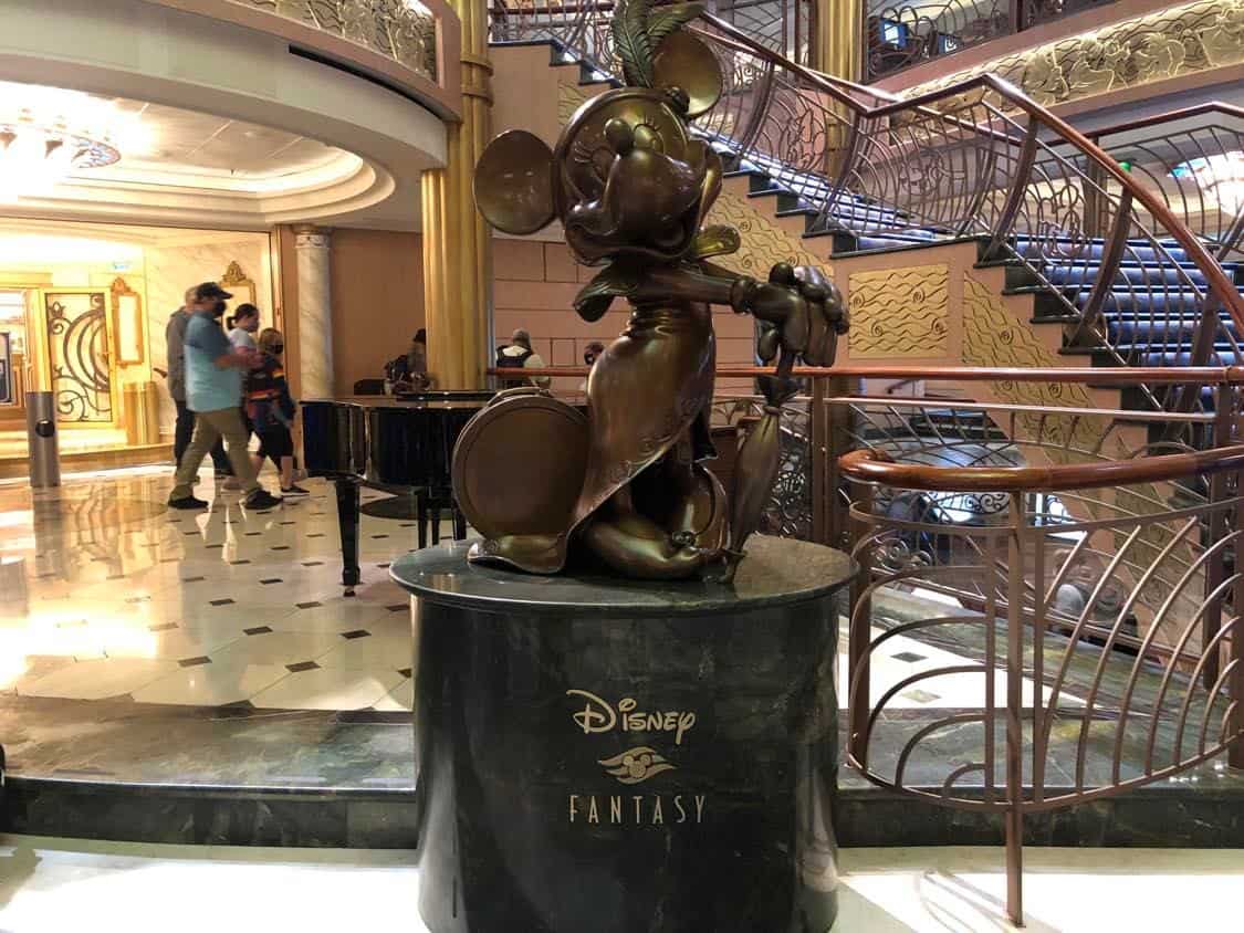 Minnie Mouse bronze statue stands proudly atop a black pedestal labeled "Disney Fantasy" in the ship’s magnificent lobby, capturing the spirit and excitement of Disney Cruise Line and commemorating the 2023 Pixar Day at Sea voyages.
